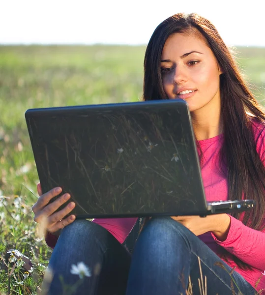 하늘에 있는 필드에 앉아 노트북으로 젊은 아름 다운 여자 — 스톡 사진
