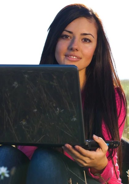 Jeune belle femme avec un ordinateur portable assis dans le champ sur le ciel — Photo