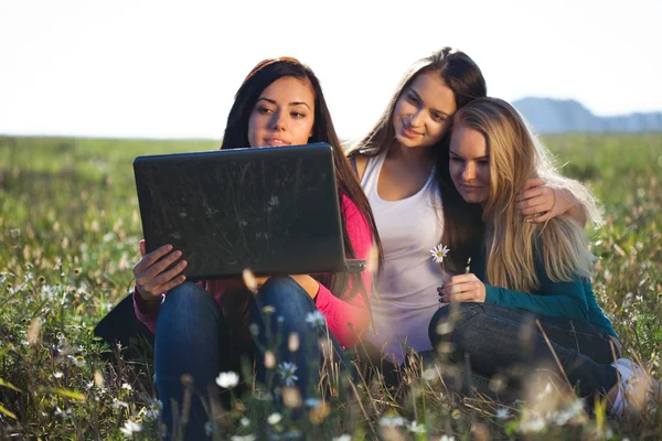 三个年轻美丽的女人坐在外地 o 一台笔记本电脑 — 图库照片
