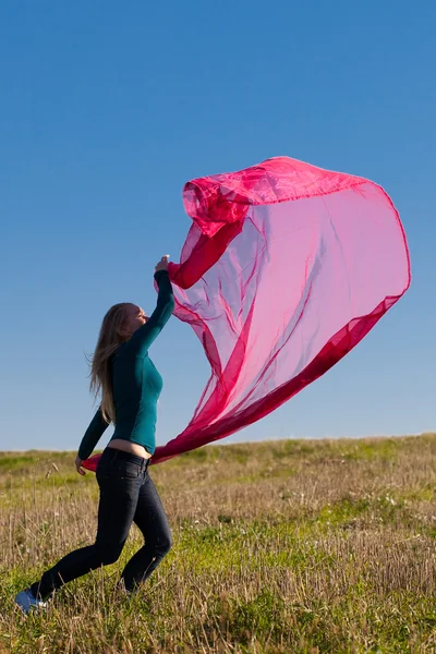 Молода красива жінка стрибає з тканиною в поле проти — стокове фото