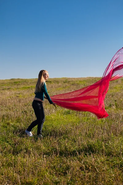Junge schöne Frau springt mit Gewebe ins Feld gegen — Stockfoto