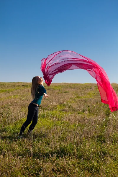 Joven hermosa mujer saltando con tejido en el campo contra —  Fotos de Stock