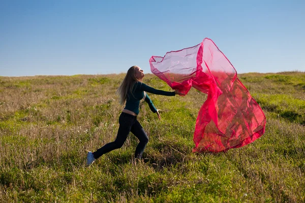 Joven hermosa mujer saltando con tejido en el campo contra —  Fotos de Stock