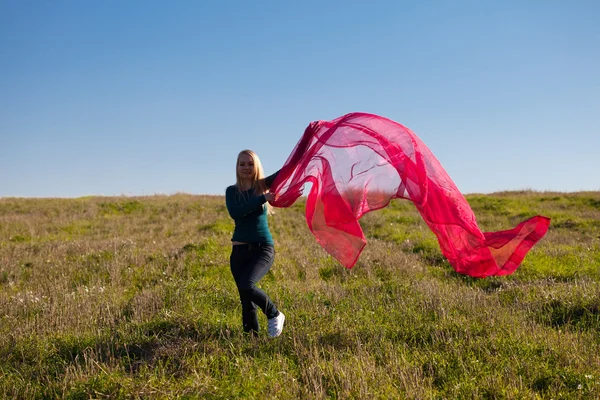 Młoda kobieta piękne skoki z tkanki w pole przeciwko — Zdjęcie stockowe