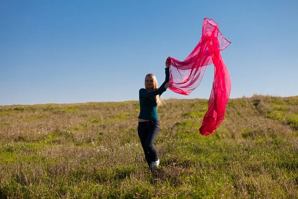Молодая красивая женщина прыгает с тканями в поле против — стоковое фото