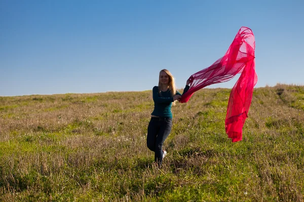 Молодая красивая женщина прыгает с тканями в поле против — стоковое фото