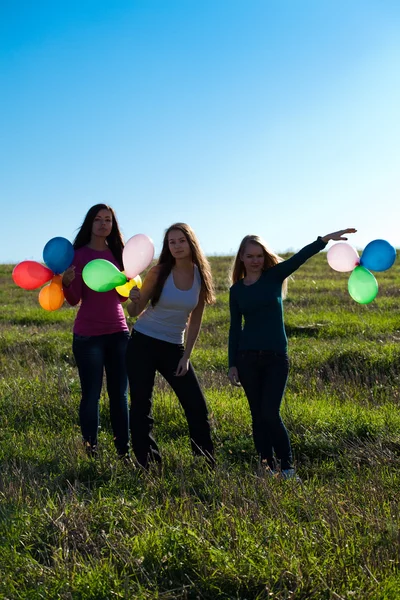 Três jovem mulher bonita com balões no campo contra — Fotografia de Stock