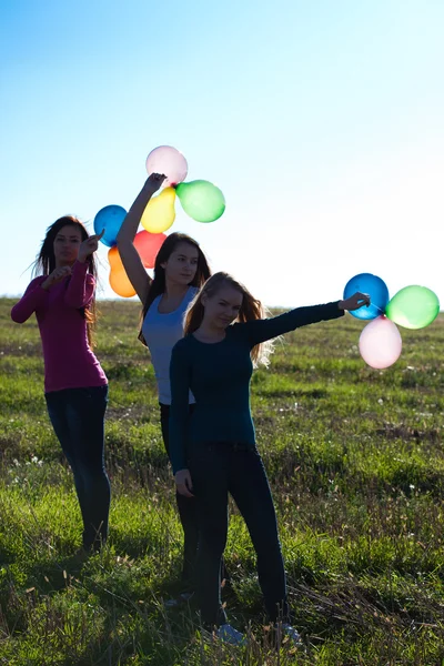 Trois jeunes belle femme avec des ballons dans le champ contre — Photo