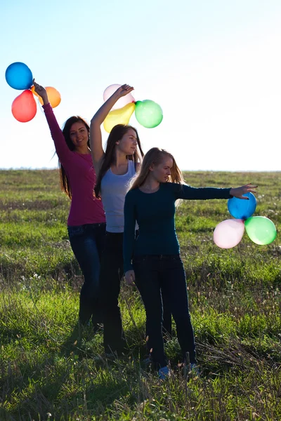Drie jonge mooie vrouw met ballonnen in het gebied tegen — Stockfoto