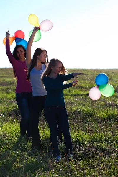 Trzech młodych piękna kobieta z balonami w pole przeciwko — Zdjęcie stockowe