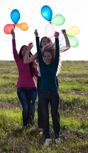 Tres mujeres hermosas jóvenes con globos en el campo contra —  Fotos de Stock