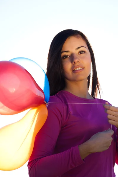 Młoda piękna kobieta z balonami w polu przed s — Zdjęcie stockowe