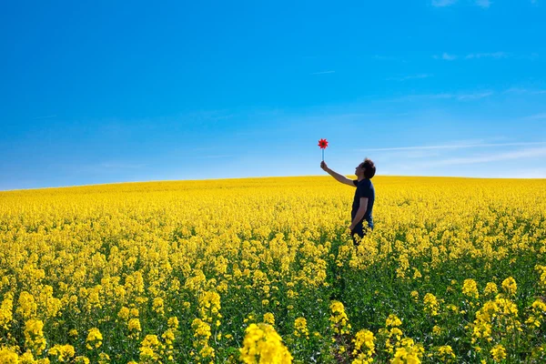 Homme à roue dentée debout dans un champ de viol jaune contre le — Photo