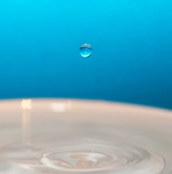 Kapka vody a splash na modrém pozadí — Stock fotografie