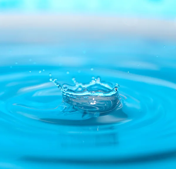 Gota de água e respingo em um fundo azul — Fotografia de Stock