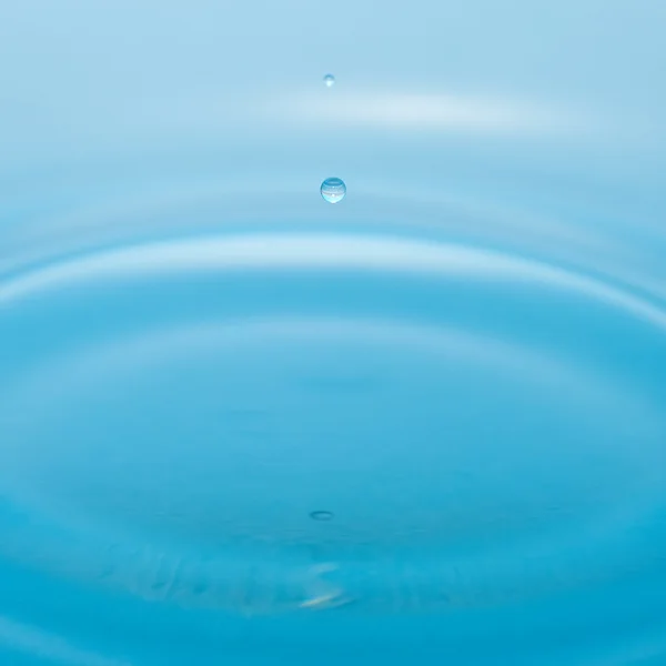 Gota de agua y salpicadura sobre un fondo azul —  Fotos de Stock