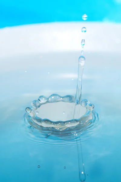Respingo de água em uma xícara em um fundo azul — Fotografia de Stock