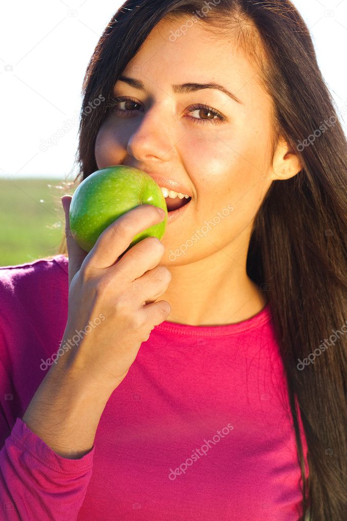 Portrait of a beautiful young woman with apple outdoor