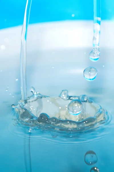 Брызги воды в чашке на синем фоне — стоковое фото