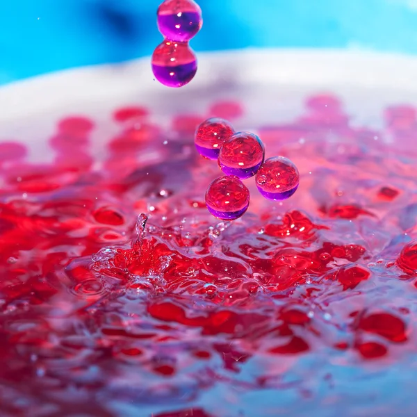 Grânulos decorativos em um spray de água em um fundo azul — Fotografia de Stock
