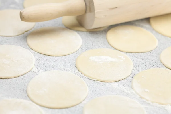 Forme ronde de la pâte et rouleau à pâtisserie avec de la farine sur la table — Photo