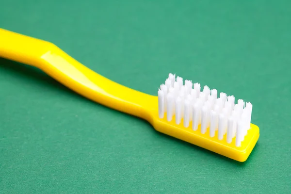 Cepillo de dientes amarillo sobre un fondo verde — Foto de Stock