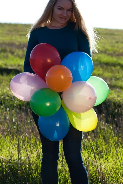 Jovem mulher bonita com balões no campo contra o s — Fotografia de Stock
