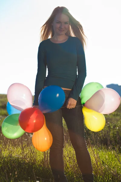 Ung vacker kvinna med ballonger i fältet mot s — Stockfoto