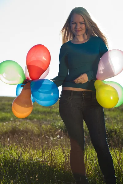 Giovane bella donna con palloncini in campo contro la s — Foto Stock