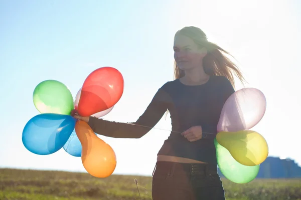 Młoda piękna kobieta z balonami w polu przed s — Zdjęcie stockowe