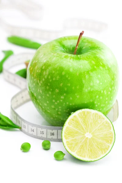 Pomme, citron vert, petits pois et ruban à mesurer isolé sur blanc — Photo