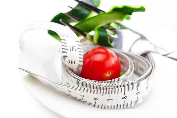 Tomate, garfo, pele de pepino e fita métrica em uma chapa isolada — Fotografia de Stock