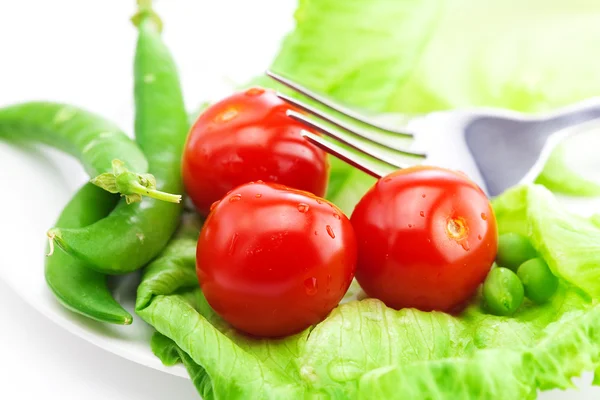 Tomaten, Erbsen und Salat mit einer Gabel auf einem Teller isoliert auf weiß — Stockfoto