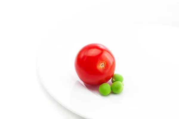 Tomat och ärtor på en tallrik som isolerad på vit — Stockfoto