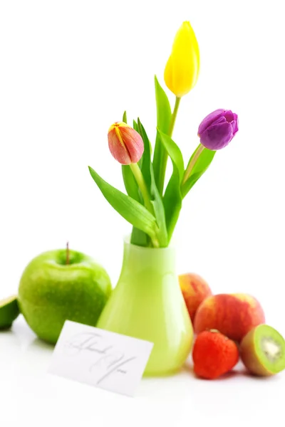 Coloridos tulipanes en jarrón, frutas y una tarjeta firmada gracias isola — Foto de Stock