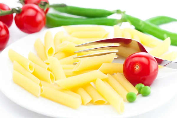 Tomates, guisantes, pasta y tenedor en un plato aislado en blanco —  Fotos de Stock
