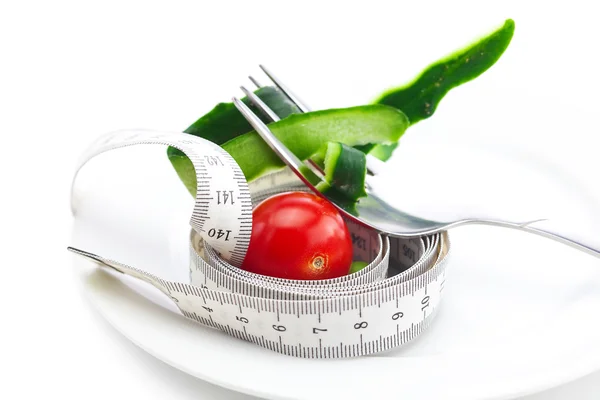 Tomato,fork ,cucumber skin and measure tape on a plate isolated — Stock Photo, Image