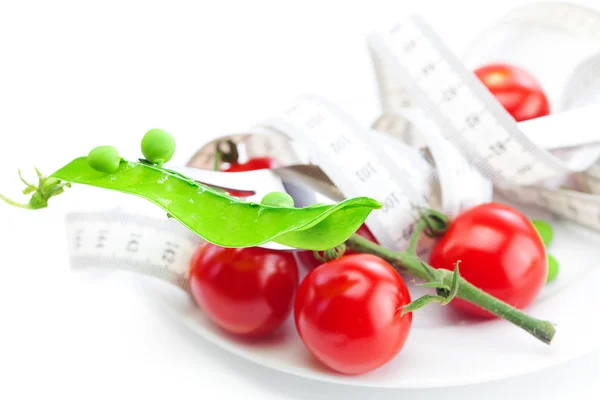 Pomidor, groszek i centymetrem na płytce na białym tle — Zdjęcie stockowe