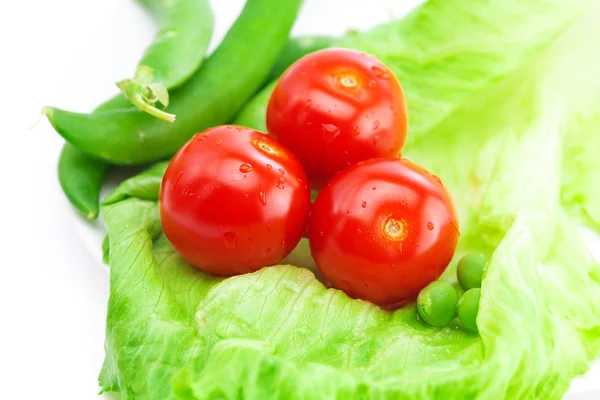 Tomato,peas and lettuce on a plate isolated on white — Stock Photo, Image