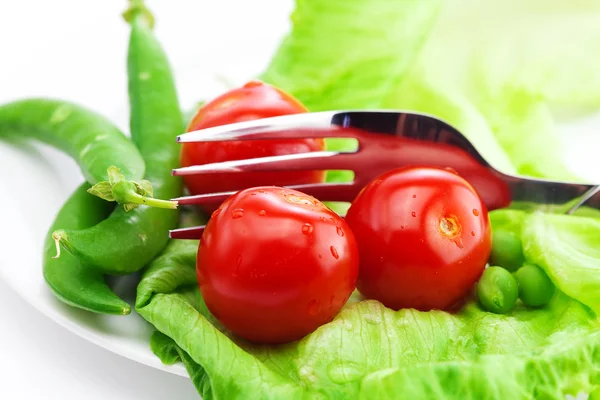 Tomaten, Erbsen und Salat mit einer Gabel auf einem Teller isoliert auf weiß — Stockfoto