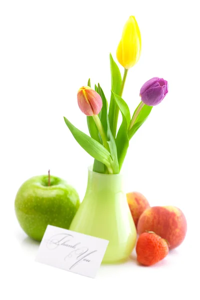 Tulipes colorées dans un vase, fraises, pomme, pêche et un panneau de carte — Photo