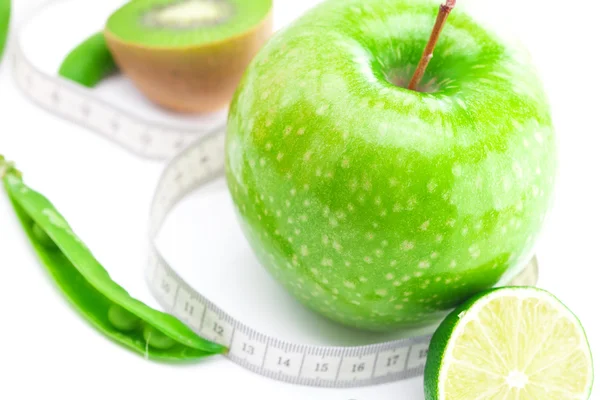 Pomme, citron vert, pois, kiwi et ruban à mesurer isolé sur blanc — Photo