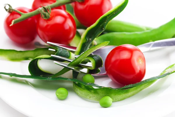 Tomato,fork ,cucumber skin,peas and measure tape on a plate isol — Stock Photo, Image