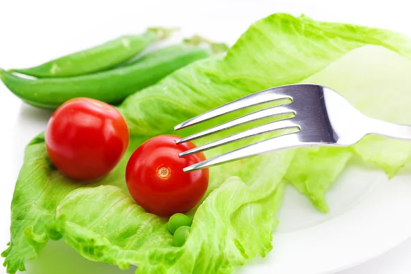 Tomato,peas and lettuce with a fork on a plate isolated on white — Stock Photo, Image