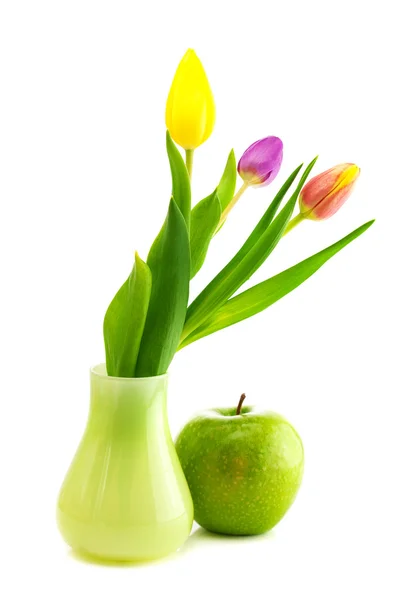 Tulipanes coloridos en jarrón y manzana aislados en blanco — Foto de Stock