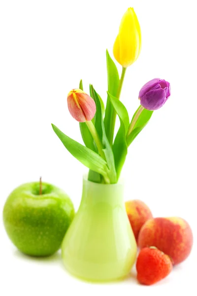 Kolorowe tulipany w wazonie, truskawki, jabłko i brzoskwinia na tle — Zdjęcie stockowe