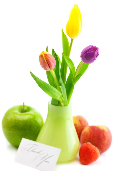 Colorful tulips in vase,strawberries,apple,peach and a card sign — Stock Photo, Image