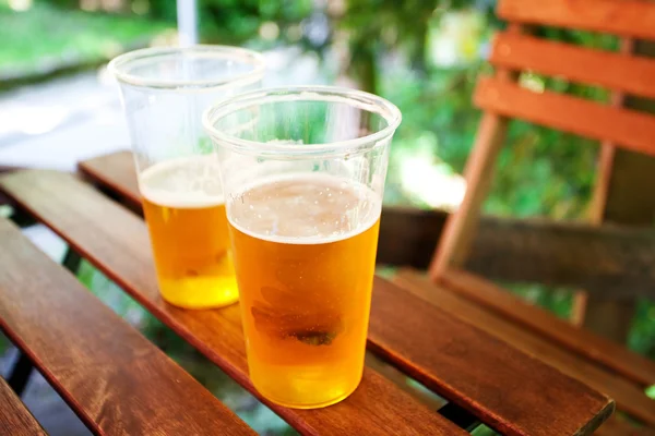 Szklanka piwa stojąc na drewnianym stołem — Zdjęcie stockowe