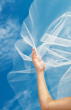 Wedding dress and veil with a hand against the blue sky clipart