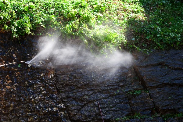 Straal water tegen de steen en groen — Stockfoto
